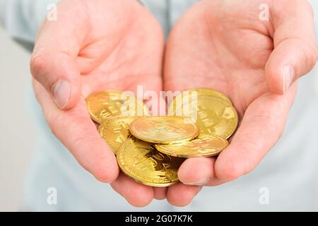 Gold Bitcoin Münzen in mans Hand. Zahlungskonzept für Kryptowährungen. Stockfoto