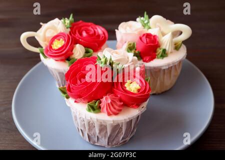 Teller mit atemberaubenden Blumenstrauß geformten Zuckerguss Cupcakes auf dunkelbraunem Hintergrund Stockfoto