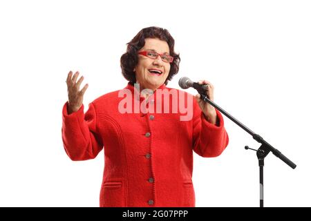Ältere Dame in einem roten Mantel, die auf einem Mikrofon singt, das auf weißem Hintergrund isoliert ist Stockfoto