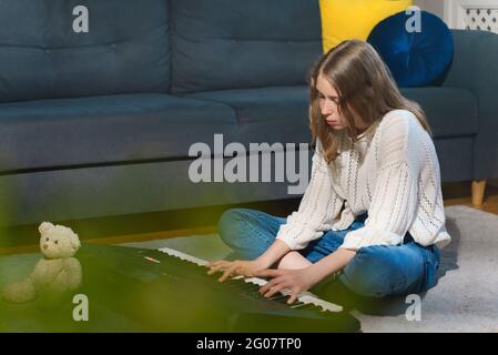 Teenagermädchen, die auf dem Boden sitzt und Klavier spielt. Stockfoto