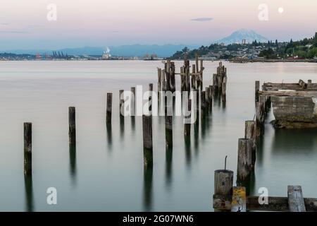 Blick auf den alten Pier bei Sonnenuntergang in ruhigem Wasser mit Berg im Hintergrund Stockfoto