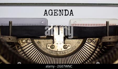 Business- und Agenda-Symbol. Das Konzeptwort 'Agenda' wurde auf der Retro-Schreibmaschine geschrieben. Schöner weißer Hintergrund. Geschäfts- und Agendakonzept. Stockfoto