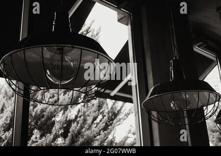 Das Fragment des Innenraums des Cafés mit den Lampen und ihrem Schatten. Schwarzweiß-Foto Stockfoto