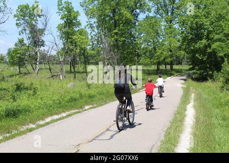 Mutter mit ihren beiden Söhnen, die auf dem North Branch Trail in Miami Woods in Morton Grove, Illinois, Fahrrad fahren Stockfoto