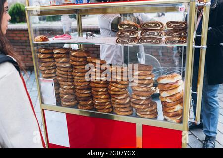 Weibchen im Stehen mit frischen Brötchen aus der Vitrine in der Nähe ausschneiden Getreideverkäufer auf der Stadtstraße in der Türkei Stockfoto