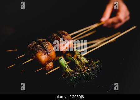 Hand halten lecker gekocht würzigen Spieße mit Fleisch und gesund Brokkoli Stockfoto