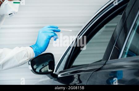 Biologe mit Schutzhandschuhen, der einen Coronavirus-Test an einem durchführt Person in einem Auto Stockfoto