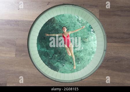 Overhead von asiatischen Weibchen mit offenen Armen und geschlossenen Augen Im Badeanzug entspannen im Pool auf den Malediven Stockfoto