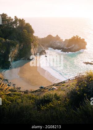 Hoher Winkel der wunderbaren Landschaft des stürmischen Ozeans Wasser mit Schaumwellen waschen den Sandstrand gegen die neblige Hochlandküste unter Grauer Himmel in Big Sur Stockfoto