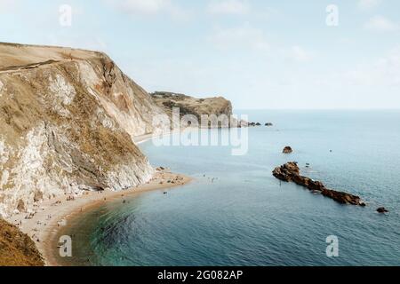 Von oben idyllische Seenlandschaft mit Felsen genannt Durdle Door und Menschen, die sich am Sommertag an der Küste entspannen Stockfoto