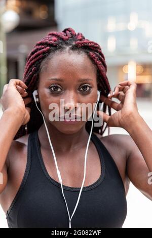Muskulöse ethnische Frau, die Musik hört Stockfoto
