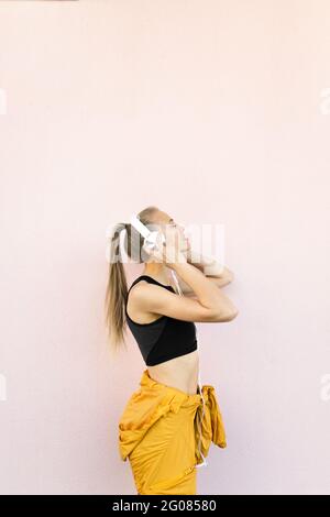 Junge kaukasische Frau, die Kopfhörer und Sport-Outfit trägt und Musik hört Stockfoto