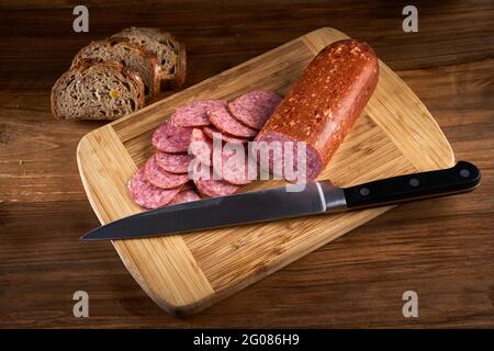 Geräucherte trockene italienische Salami in Scheiben auf einem Holzbrett Stockfoto