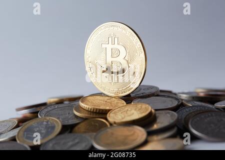 Goldene und glänzende Bitcoin-Münzen auf verschiedenen Weltwährungen, die eine Auswahl an verschiedenen Zahlungs- und Anlageoptionen darstellen. Stockfoto