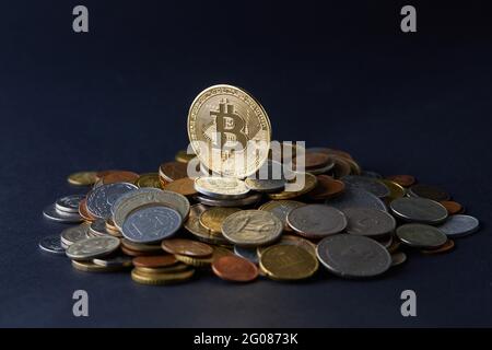 Goldene und glänzende Bitcoin-Münzen auf verschiedenen Weltwährungen, die eine Auswahl an verschiedenen Zahlungs- und Anlageoptionen darstellen. Stockfoto