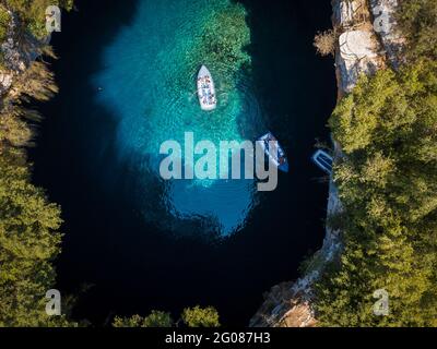 Ein paar Ausflugsboote, die auf der Oberfläche von klarem Wasser in der Höhle Melissani schwimmen Stockfoto
