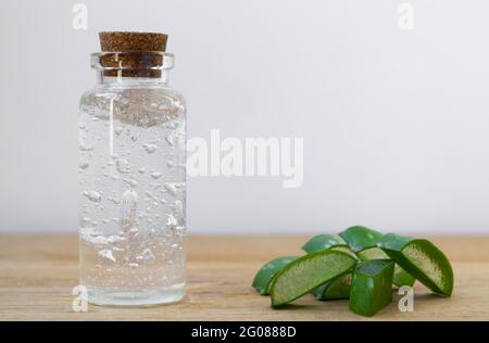 Glasflasche aus Aloe Vera Gel mit Blattpflanzen auf Holzgrund Stockfoto