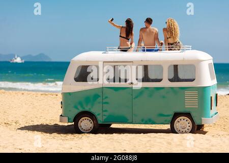 Glückliche Freunde, die Fotos machen, während sie sich auf dem Minibus entspannen Stockfoto