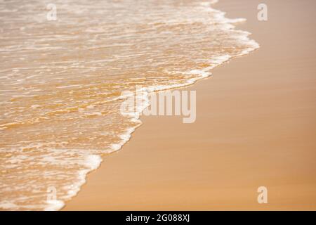 Nahaufnahme von hellen, schäumenden Wellen am Sandstrand Stockfoto