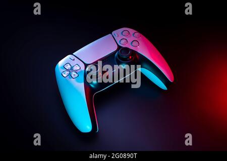 Modernes weißes Gamepad in rot und blau beleuchtet. Game Controller für Videospiele und E-Sports auf dunklem Hintergrund. Stockfoto