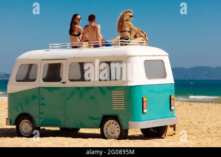 Drei Freunde, die sich auf dem Retro-Bus am Meer entspannen Stockfoto