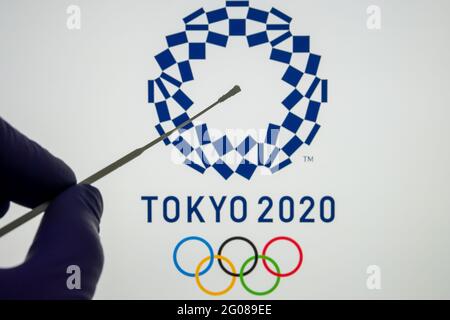 Negativer PCR-Test vor und verschwommenes Tokyo 2020-Logo auf dem verschwommenen Hintergrund. Konzept für die Olympischen Spiele des COVID in Tokio im Jahr 2021. Stafford, United King Stockfoto