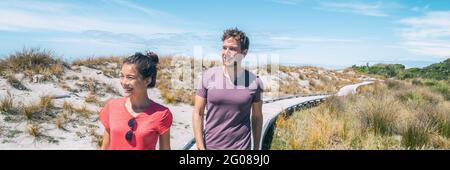 Ein paar Touristen, die auf der Ship Creek Strandpromenade unterwegs sind, während eines Sommerurlaubs an der Westküste, Südinsel Neuseelands. Panorama-Banner Stockfoto