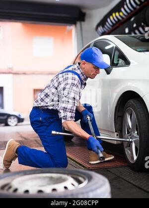 Der qualifizierte Mechaniker wechselt die Reifen des Fahrzeugs im Autodienst Stockfoto