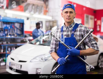 Der qualifizierte Mechaniker wechselt die Reifen des Fahrzeugs im Autodienst Stockfoto