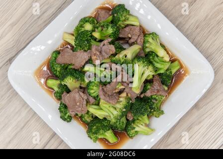 Blick von oben auf einen großen Stapel würziger thailändischer Brokkoli, serviert mit Fleisch und Sauce auf einem Teller. Stockfoto