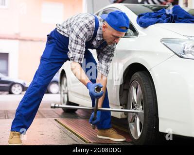 Der qualifizierte Mechaniker wechselt die Reifen des Fahrzeugs im Autodienst Stockfoto