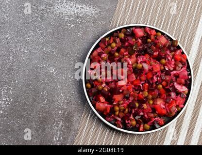 Traditionelle Vinaigrette - Salat aus Rote Beete und Gemüse auf einem runden Teller auf dunklem Grund. Draufsicht, flach liegend Stockfoto