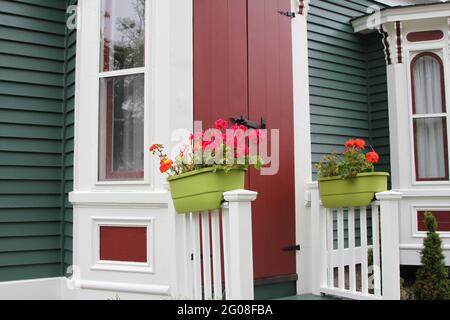 Bunte Blumen in Töpfen auf Geländern des viktorianischen Hauses Stockfoto