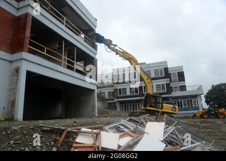 GREYMOUTH, NEUSEELAND, 19. Januar 2021: Ein Bagger nutzt einen Klauenaufsatz, um das alte Krankenhausgebäude in Greymouth, Neuseeland, im Januar abzureißen Stockfoto