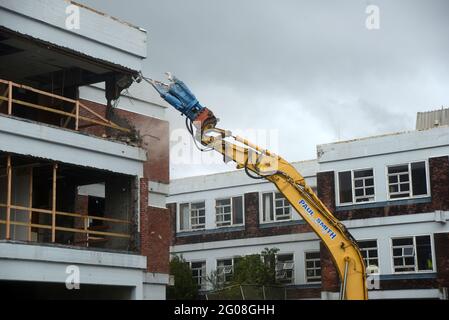 GREYMOUTH, NEUSEELAND, 19. Januar 2021: Ein Bagger nutzt einen Klauenaufsatz, um das alte Krankenhausgebäude in Greymouth, Neuseeland, im Januar abzureißen Stockfoto