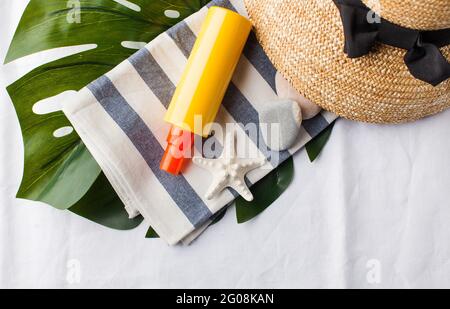 Summer background. Hat, seashells, sunscreen on a white towel. Copy space. Stockfoto