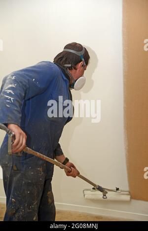 Ein Handwerker, der Airless-Sprühgeräte verwendet, um einen Grundierlack an die Wände eines Geschäftsgebäudes zu streichen Stockfoto