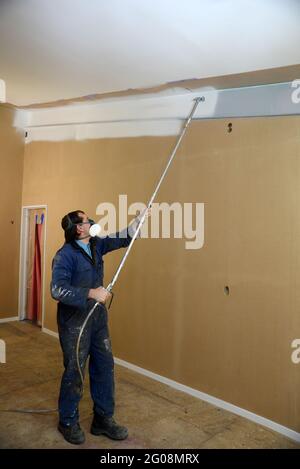 Ein Handwerker, der Airless-Sprühgeräte verwendet, um einen Grundierlack an die Wände eines Geschäftsgebäudes zu streichen Stockfoto
