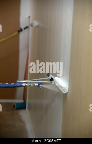 Detail der Airless-Spritzgeräte, die zum Lackieren einer Grundierung an den Wänden eines Geschäftsgebäudes verwendet wurden Stockfoto