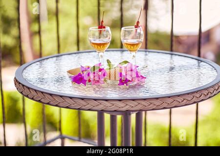 Sommer kreative surreale Blumen und hausgemachte Getränke auf Glastisch an sonnigen Sommertag auf dem Balkon. Romantisches Dinner-Konzept. Sommer heller Hintergrund. Hochwertige Fotos Stockfoto