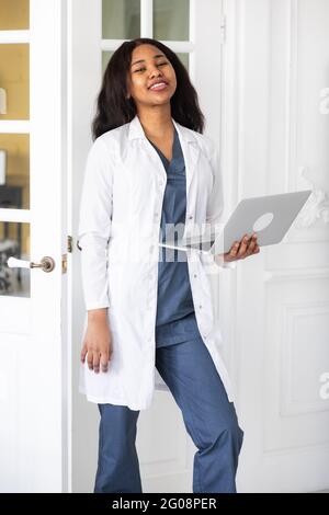 Gutaussehende, zufriedene afroamerikanische Ärztin, die an einem Laptop arbeitet. Telemedizin Stockfoto