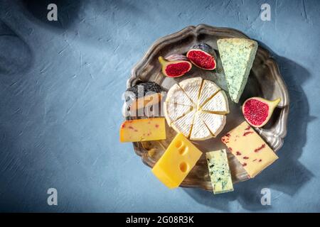 Käseplatte und eine Silhouette eines Glases Wein, Top-Shot mit einem Platz für Text. Brie, Blauschimmelkäse und andere Sorten Stockfoto