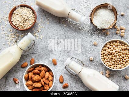 Alternative Arten von veganen Milchsorten in Glasflaschen auf betontem Hintergrund. Draufsicht Stockfoto