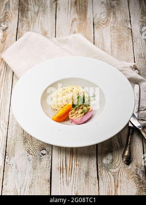 Risotto mit Meeresfrüchten. Ei mit geräucherter Makrelenpastete. Honigorange-Tomate. Gourmetküche. Food-Fotografie und Styling. Mediterrane Küche. Vertic Stockfoto