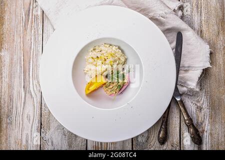 Risotto mit Meeresfrüchten. Ei mit geräucherter Makrelenpastete. Honigorange-Tomate. Gourmetküche. Food-Fotografie und Styling. Mediterrane Küche. Vertic Stockfoto