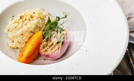 Risotto mit Meeresfrüchten. Ei mit geräucherter Makrelenpastete. Honigorange-Tomate. Gourmetküche. Food-Fotografie und Styling. Mediterrane Küche. Delikatesse Stockfoto