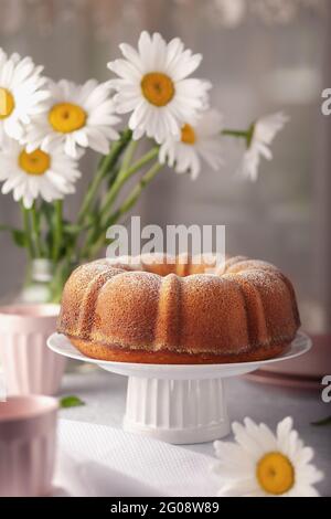 Runder Cupcake mit einem Loch auf einer weißen Schale, bestreut mit Puderzucker Stockfoto