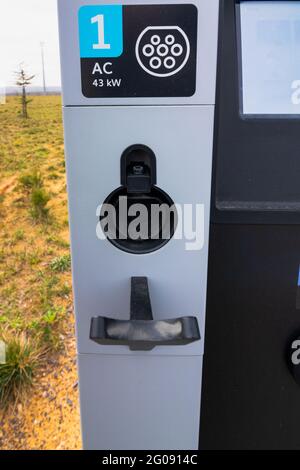 Nicht eingestecktes EV-Ladegerät an der EV-Ladestation im Fokus. Schnelles Ladegerät für Elektroautos. Ladestation für Elektrofahrzeuge. Stockfoto