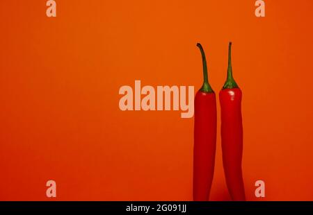 2 Chilischoten auf orangefarbenem Hintergrund Stockfoto