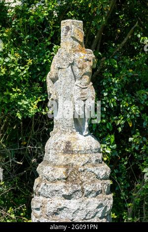 Eine stark beschädigte Statue von zwei Figuren, eine Christusfigur, ein Kreuz auf einer Steinsäule am Straßenrand in der Nähe von Bruisyard Hall, Suffolk, Großbritannien Stockfoto